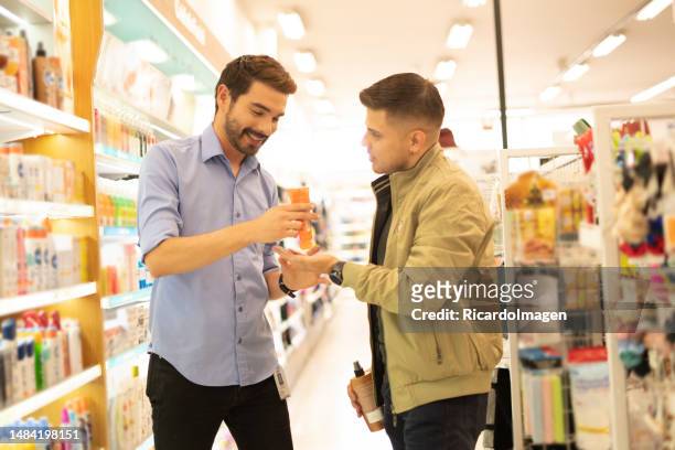 homem latino está dentro da loja comprando seus cuidados enquanto é aconselhado por um dos vendedores da loja - color tipo de imagen - fotografias e filmes do acervo