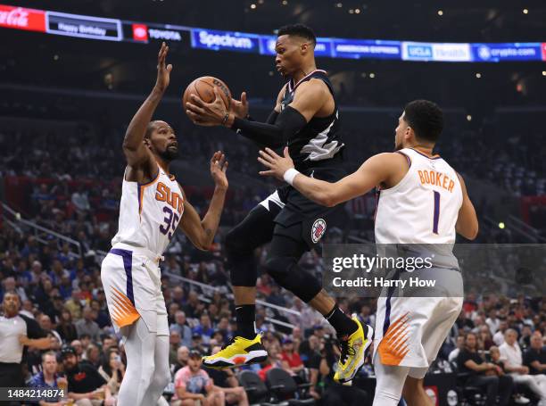 Russell Westbrook of the LA Clippers makes a pass as he cuts between Kevin Durant and Devin Booker of the Phoenix Suns during the first quarter of...