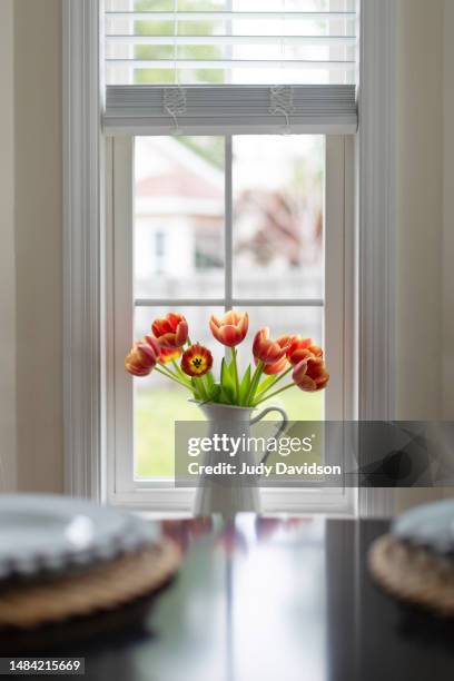 enamel pitcher with orange tulips on window sil - emaille stock-fotos und bilder