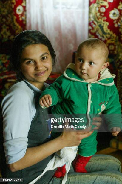 Roma girl poses with a baby inside her home at a Roma gypsy encampment on May 10, 2005 in Kosice, Slovakia. The Roma community remains one of the...