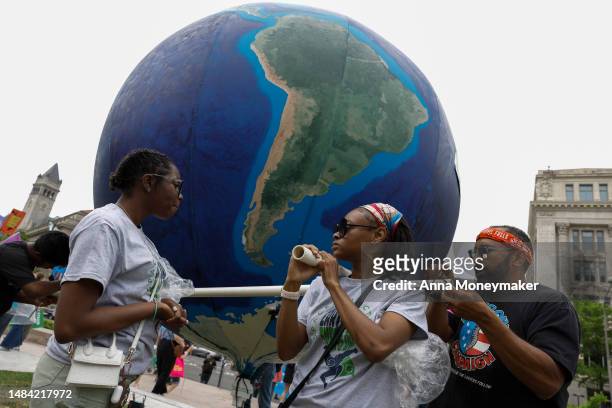 Activists work to untether an inflated replica of Earth for an Earth Day march titled “End the Era of Fossil Fuels,” at Freedom Plaza on April 22,...