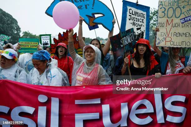 People participating in an Earth Day march titled “End the Era of Fossil Fuels,” chant in Lafayette Park during a rainstorm on April 22, 2023 in...