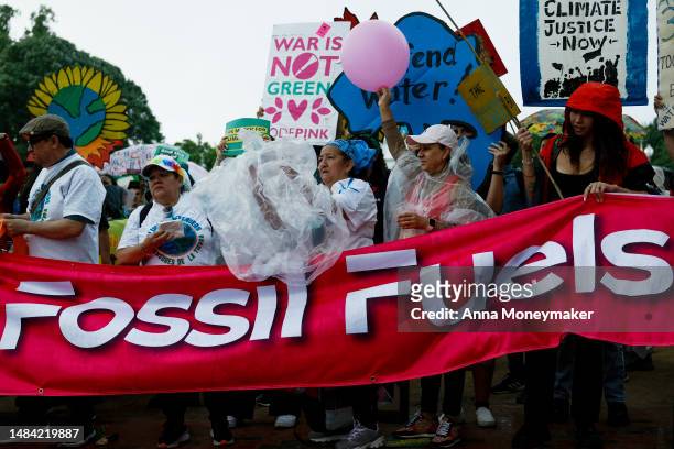 People participating in an Earth Day march titled “End the Era of Fossil Fuels,” chant in Lafayette Park during a rainstorm on April 22, 2023 in...