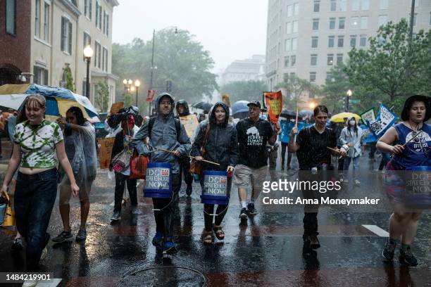 People participating in an Earth Day march titled “End the Era of Fossil Fuels,” march back to Freedom Plaza during a rainstorm on April 22, 2023 in...