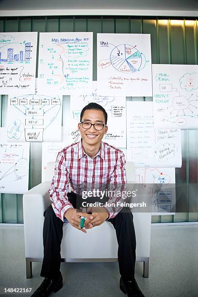 smiling businessman seated with charts - asian man sitting at desk stock pictures, royalty-free photos & images