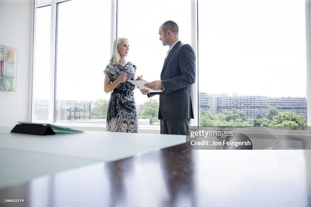 A businessman and businesswoman talking by window