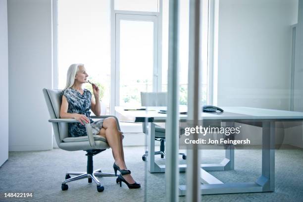 businesswoman sitting at desk contemplating - mini dress stock pictures, royalty-free photos & images