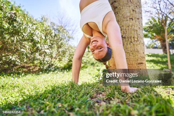 smiley woman doing exercises upside down leaning in a trunk - woman smiling facing down stock pictures, royalty-free photos & images