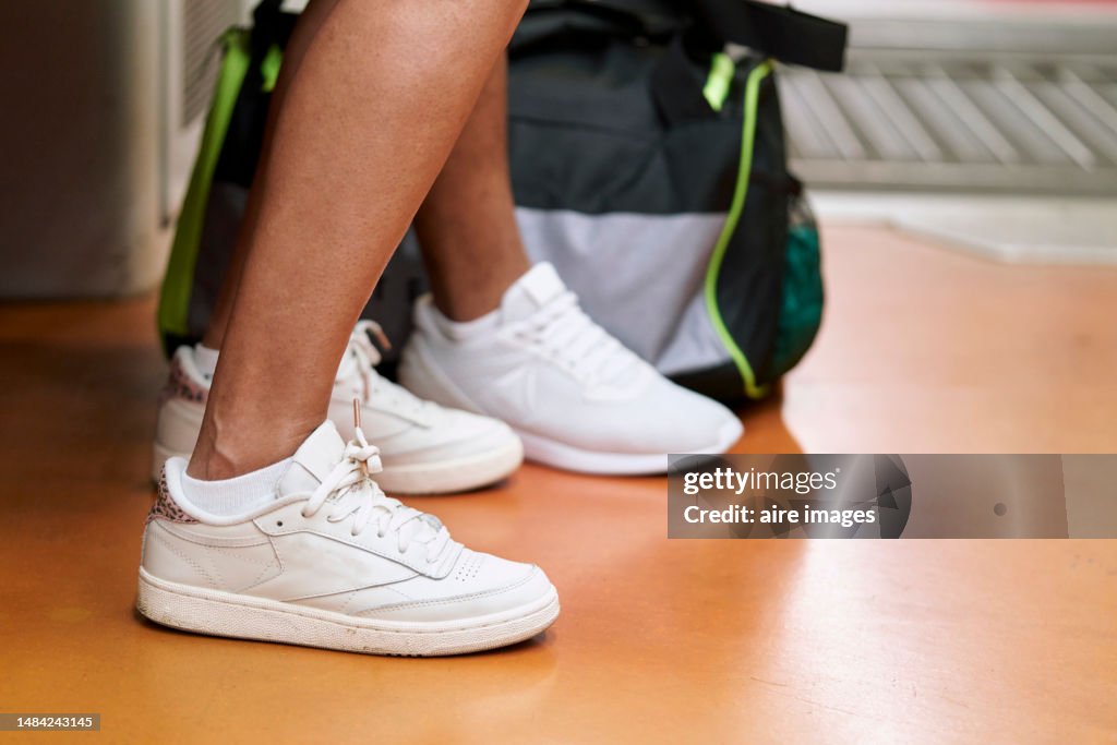 Close-up of the legs of a girl seated inside a train with her backpack on the floor, side view