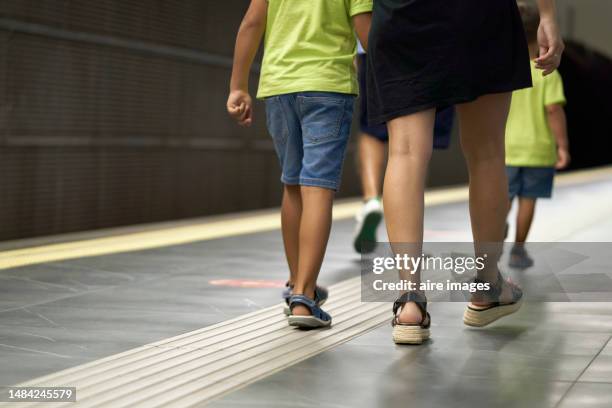 legs of woman in sandals and skirt walking in subway station holding her son's hand, rear view - boy skirt stock pictures, royalty-free photos & images