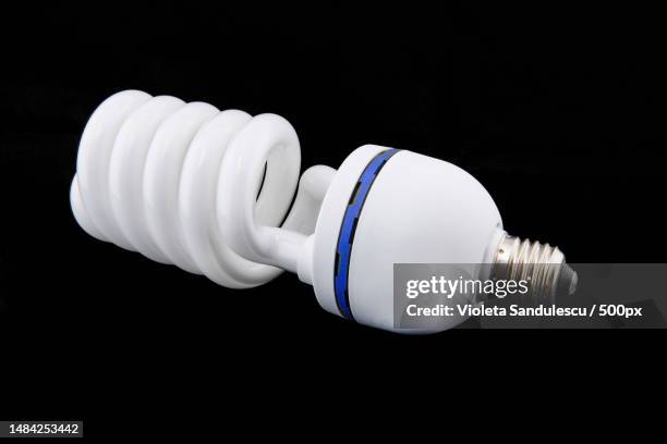 white energy saving bul or illuminated light bulb on black background - luce fluorescente foto e immagini stock
