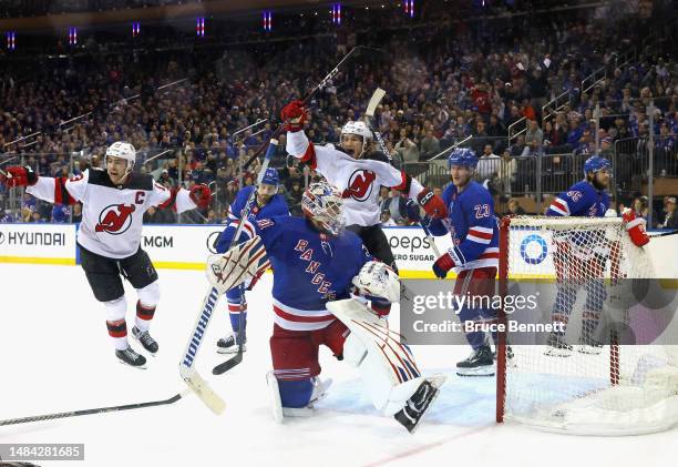 Nico Hischier and Dawson Mercer of the New Jersey Devils celebrate an overtime victory against Igor Shesterkin and the New York Rangers during Game...
