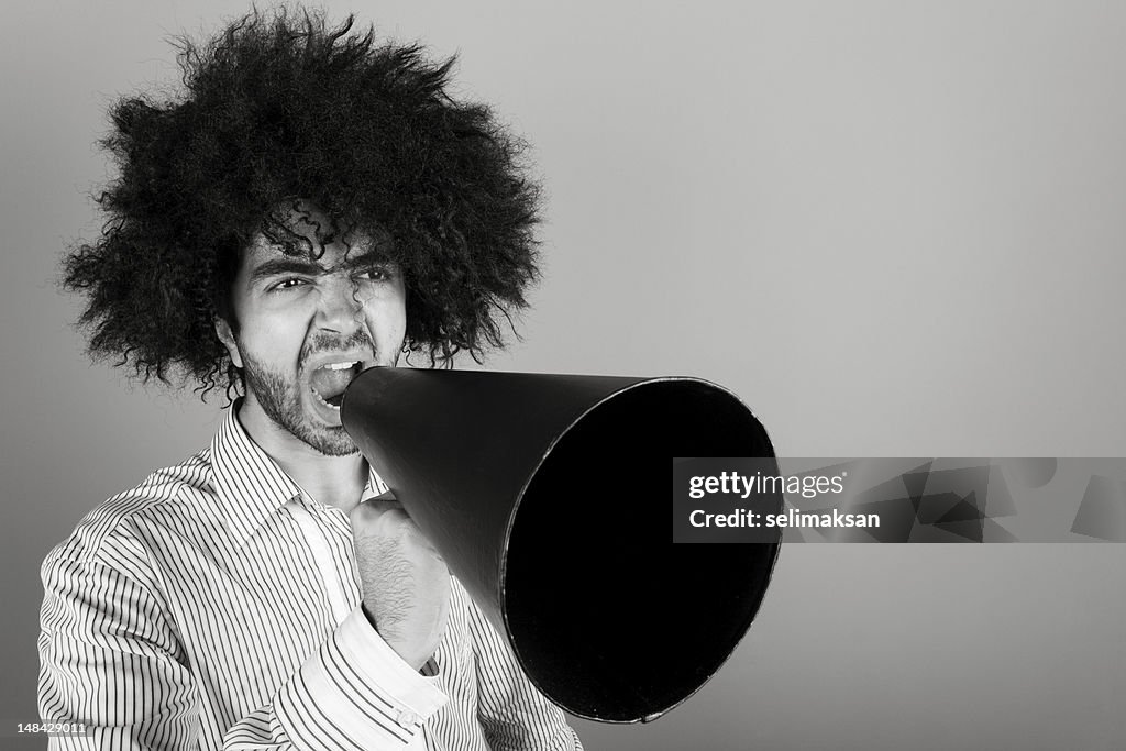 Young Man With Big Curly Hair Shouting With Megaphone