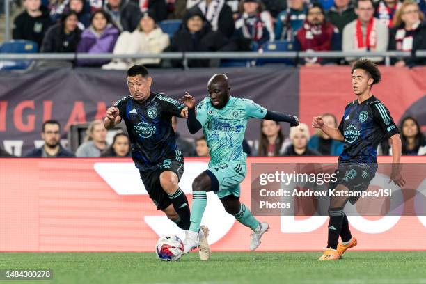 Emmanuel Boateng of New England Revolution dribbles as Roger Espinoza of Sporting Kansas City defends during a game between Sporting Kansas City and...