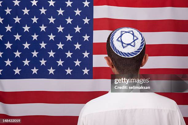 jewish citizen wearing yarmulke in front of american flag - skull cap stock pictures, royalty-free photos & images