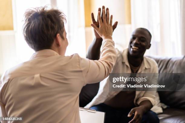 happy african-american man giving psychotherapist a high five - legal problems stock pictures, royalty-free photos & images