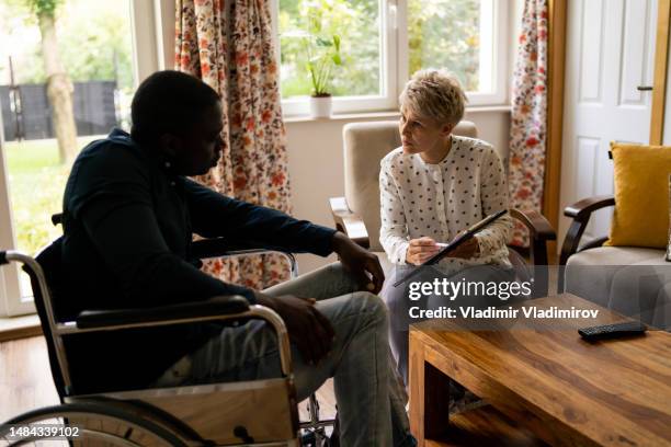 african-american wheelchair user talking to social worker - mental disability stock pictures, royalty-free photos & images