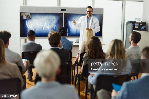 happy male doctor leading a presentation in board room. - doctor speech stock pictures, royalty-free photos & images