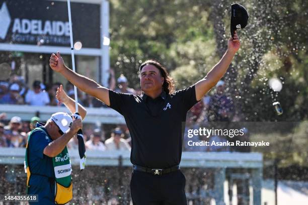 Pat Perez of 4Aces GC celebrates after making a birdie on the 12th hole as beers cans are thrown onto the green and Charl Schwartzel caddie shields...