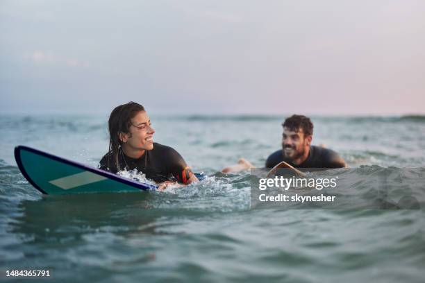 happy couple enjoying on surfboards at sea. - adventure stock pictures, royalty-free photos & images