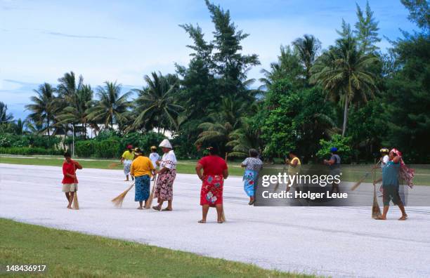 women sweeping airport runway at funafuti international airport. - tuvalu stock pictures, royalty-free photos & images