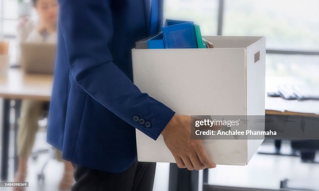 Business concept : An unemployed with her cardboard box walking out of the work office