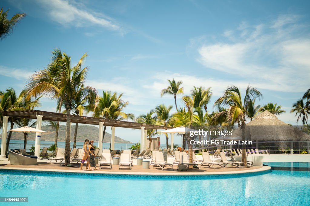 Traveler friends walking by the swimming pool on a hotel resort