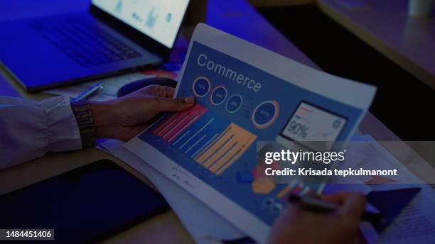 young asian businesswoman looking through documentation for quarterly meeting. - quarterly stock pictures, royalty-free photos & images