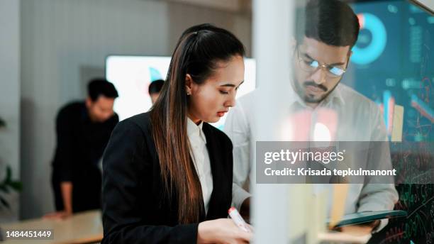 young asian man and woman preparing visual aids together before team presentation. - unveiing stock pictures, royalty-free photos & images