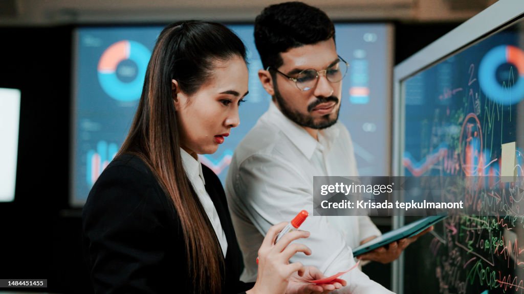 Young Asian Man and Woman Preparing Visual Aids Together Before Team Presentation.