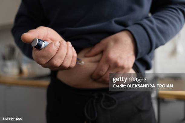 close-up of man making insulin injection in belly  with insulin pen - injecteren stockfoto's en -beelden