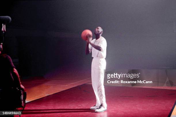 Chicago Bulls basketball player Michael Jordan is about to shoot a Wilson basketball with a sound man's equipment on the edge of the set while...