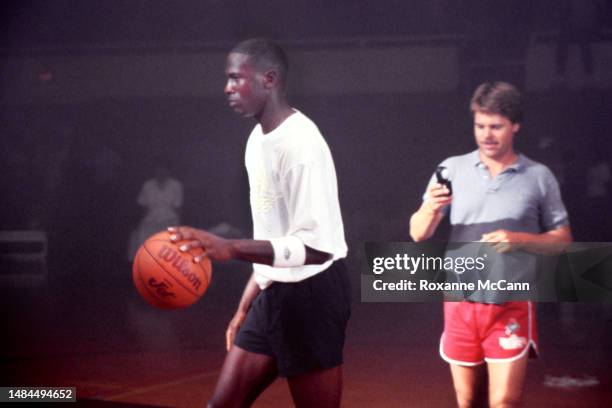 Chicago Bulls basketball player Michael Jordan plays with a Wilson basketball wearing an Air Jordan shirt while a crew member determines the camera...