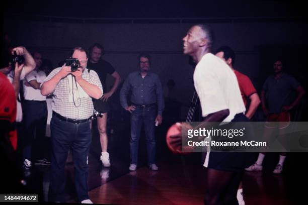 Chicago Bulls basketball player Michael Jordan is about to shoot a Wilson basketball with the crew and production teams behind him while filming a...