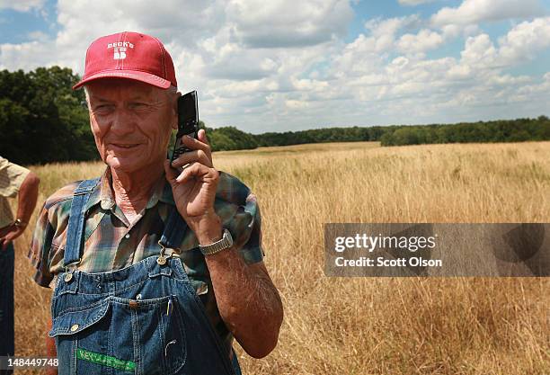 Farmer Marion Kujawa holds out his phone so his wife can listen to a press conference being held by Illinois Gov. Pat Quinn to discuss drought...