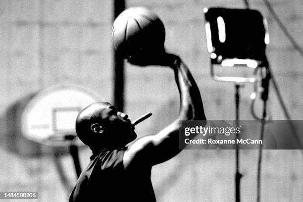 Basketball legend Michael Jordan rehearses for a television commercial while smoking a cigar on a sound stage with lighting equipment in the...