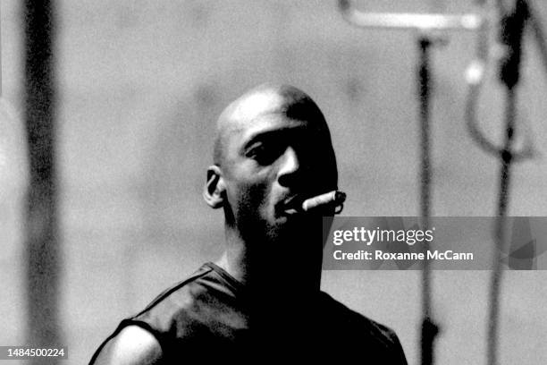 Basketball legend Michael Jordan smokes a cigar in front of lighting equipment while waiting to be filmed for a television commercial on a sound...