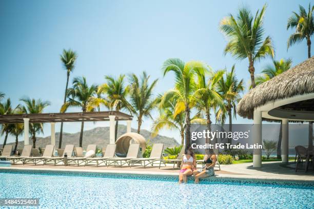 amigas viajeras hablando junto a la piscina del hotel - al lado de la piscina fotografías e imágenes de stock