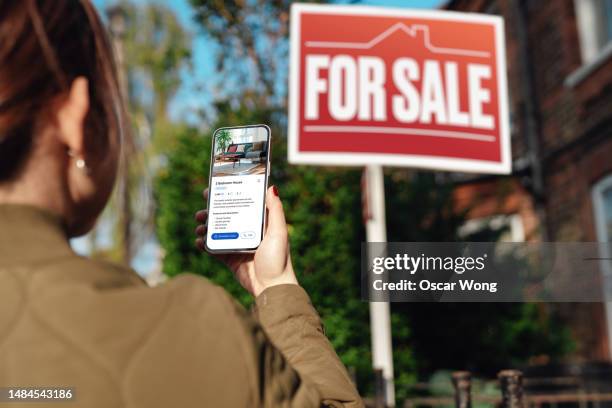 woman looking for property to buy via real estate website on smartphone - house for sale uk stock pictures, royalty-free photos & images