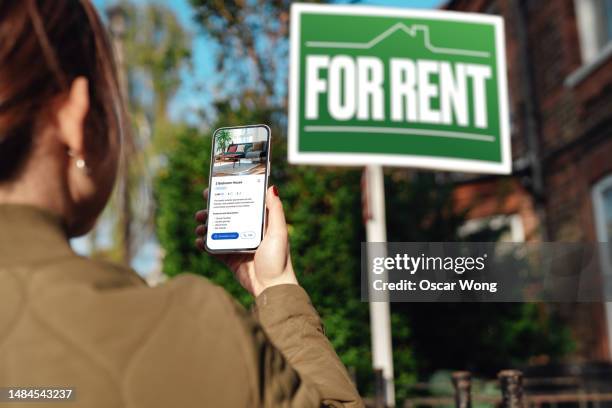 woman looking for property to rent via real estate online platform on smartphone - huurhuis stockfoto's en -beelden