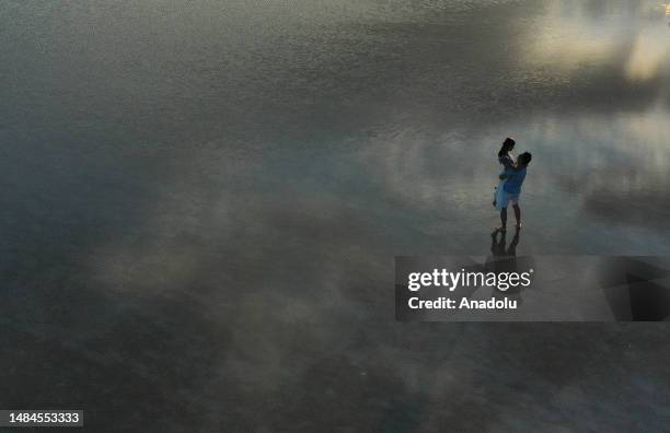 An aerial view of couple visit Lake Salt, which is on the UNESCO World Heritage Tentative List, during sunset in Ankara, Turkiye on July 04, 2023....