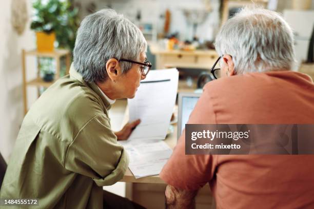 senior couple going over bills at home - elderly woman from behind stock pictures, royalty-free photos & images