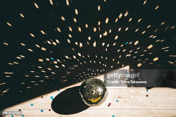 abstract afterparty shot of a morning sunlight shining on the disco ball, confetti on the floor - house after party stockfoto's en -beelden