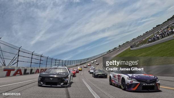 Denny Hamlin, driver of the FedEx Freight Direct Toyota, and Aric Almirola, driver of the Smithfield Ford, lead the field on a pace lap prior to the...