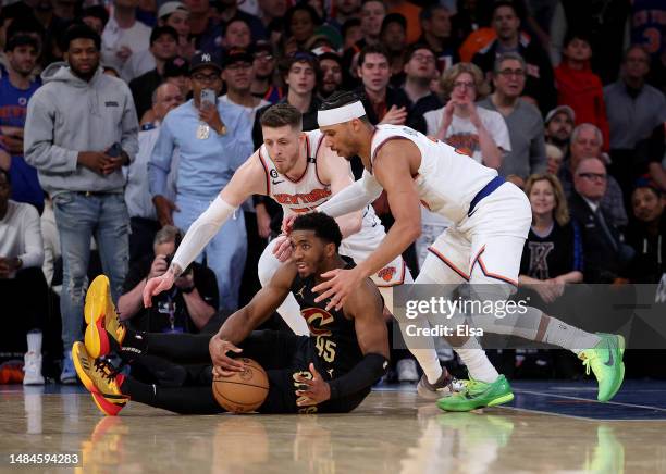 Donovan Mitchell of the Cleveland Cavaliers tries to maintain possession of the ball as Isaiah Hartenstein and Josh Hart of the New York Knicks...