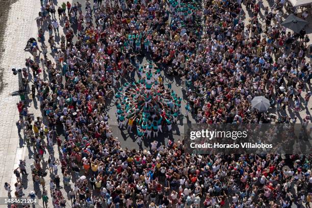 Large crowd of locals and tourists watch as Castellers de Vilafranca members climb on top of each other while building a "castell" by Padrão dos...