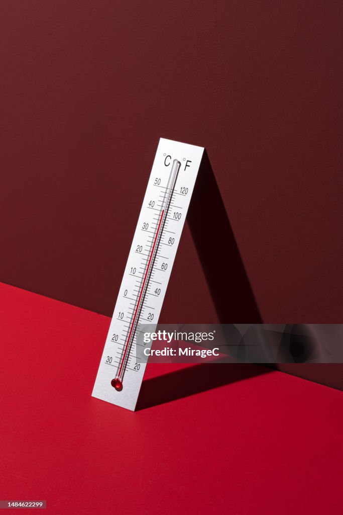 Silver Thermometer Shows High Temperature on Red Background