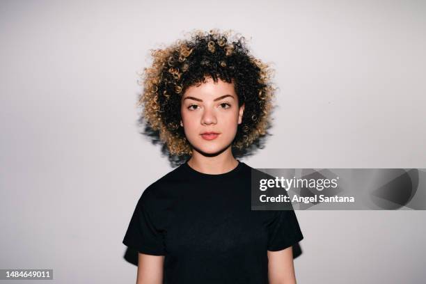 portrait of young latina with afro hair against a wall with hard frontal flash light - human face frontal stock pictures, royalty-free photos & images