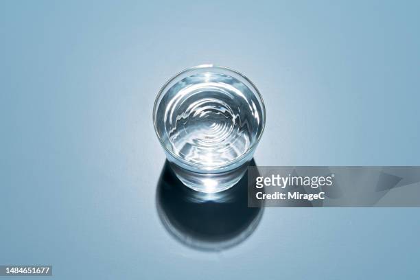 water in a glass cup on blue background - cup of water stockfoto's en -beelden