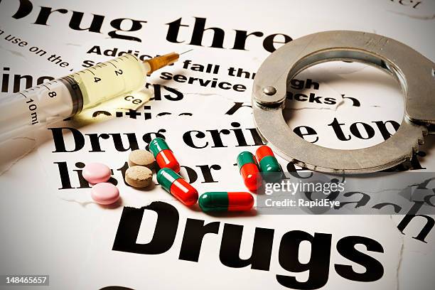 handcuff, tablets, syringe and capsules on drug headlines - western script stock pictures, royalty-free photos & images